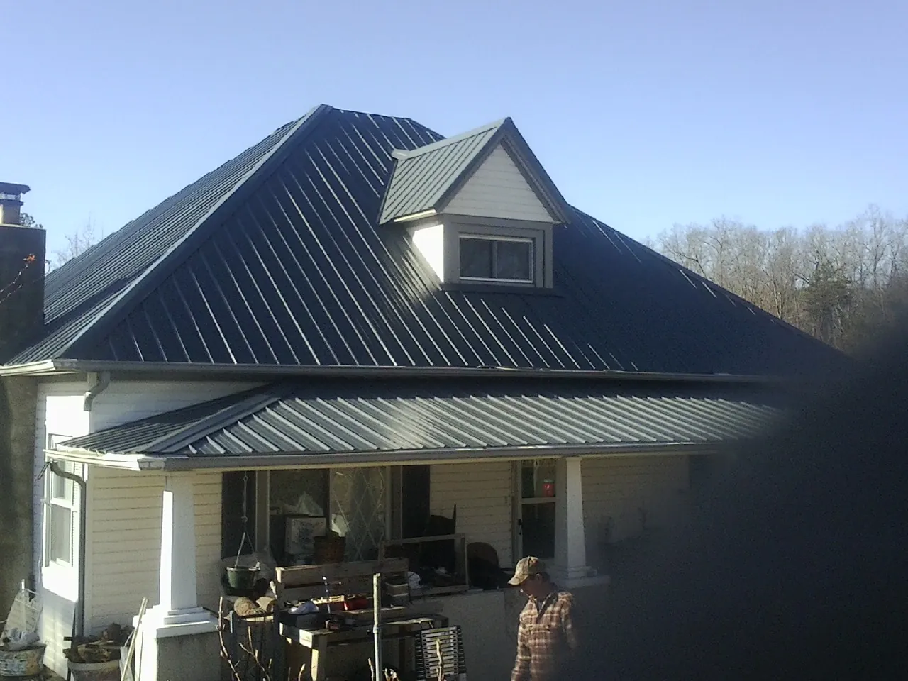 Dark blue standing seam metal roof with a dormer above a front porch in Winchester